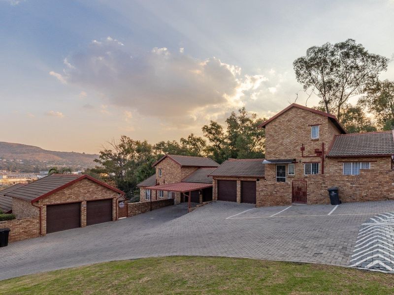 Exterior view of a townhouse complex featuring face brick construction, multiple garages, a paved driveway, and a carport.