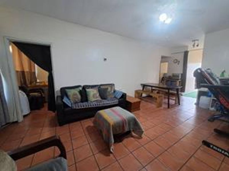 An open-plan living and dining area featuring tiled flooring and a ceiling fan, providing a functional space for daily living.
