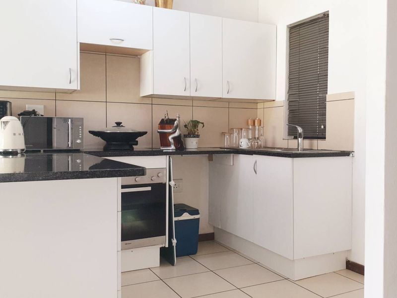 A functional kitchen featuring white cabinetry, dark granite countertops, a built-in oven, and tiled flooring with a neutral backsplash.