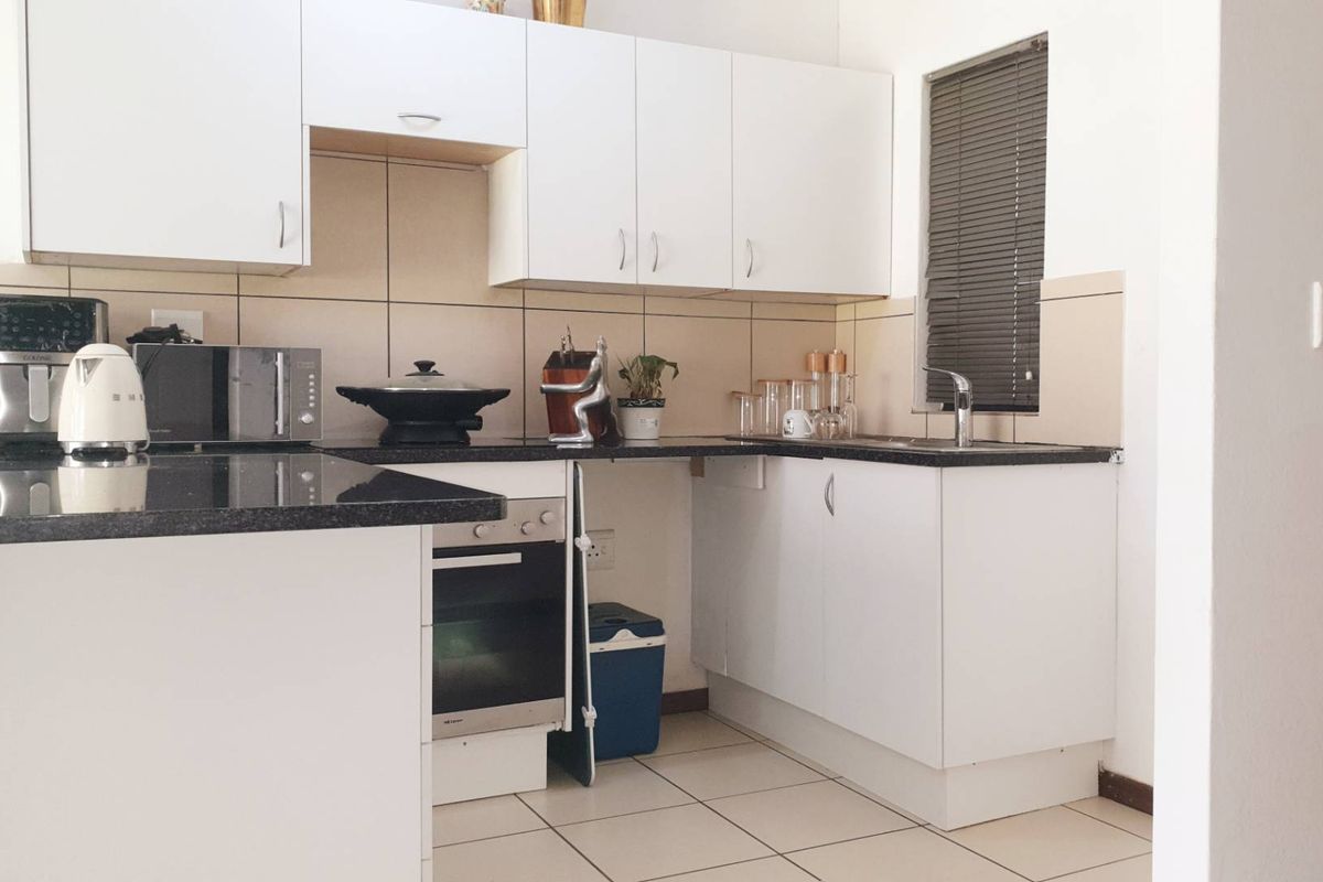 A functional kitchen featuring white cabinetry, dark granite countertops, a built-in oven, and tiled flooring with a neutral backsplash.