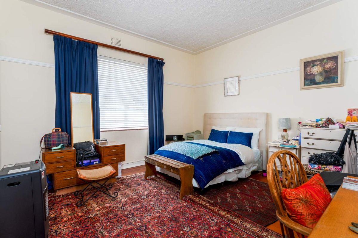 A spacious bedroom featuring classic picture rails, timber flooring, and a large window with fitted blinds, offering a comfortable and functional living space.