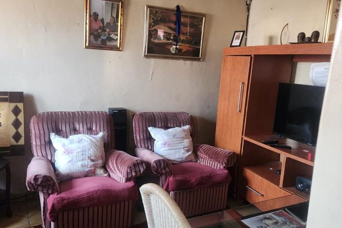 A living room area featuring tiled flooring and decorative ceiling molding, currently showing signs of wear and requiring cosmetic updates.
