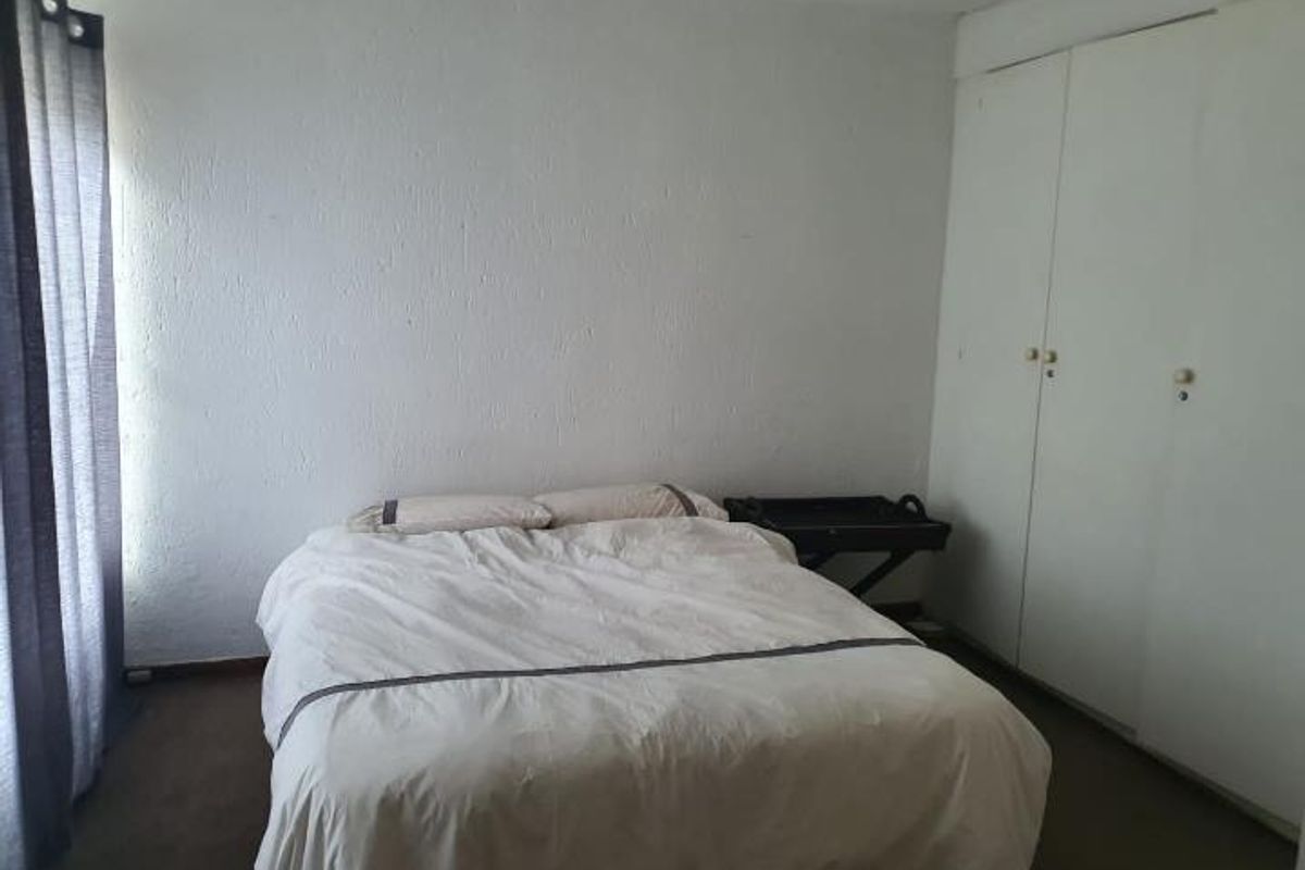 A bedroom featuring built-in cupboards and carpeted flooring, providing a functional and neutral space.