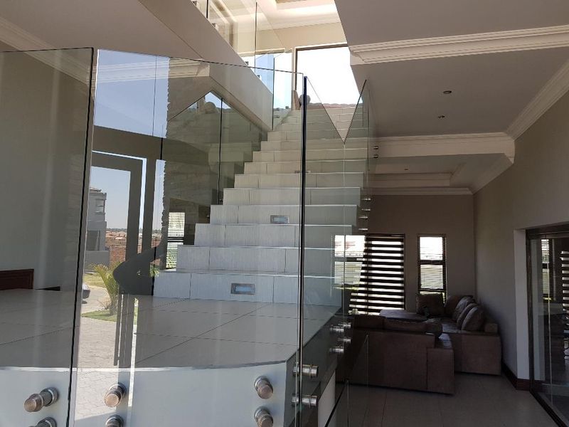 Modern entrance hall featuring a striking tiled staircase with glass balustrades, recessed lighting, and high-quality finishes throughout the open-plan living space.
