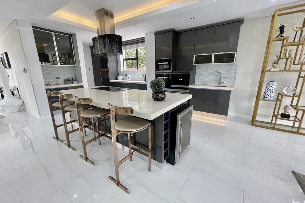 Modern kitchen featuring high-gloss cabinetry, a large central island with quartz countertops, integrated appliances, and sophisticated recessed lighting.