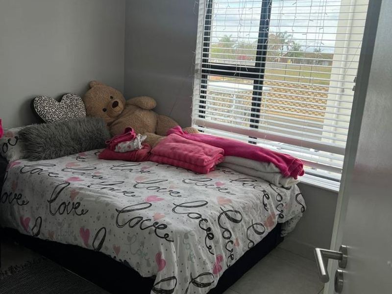 A bedroom featuring tiled flooring, neutral wall paint, and an aluminium window with fitted venetian blinds.