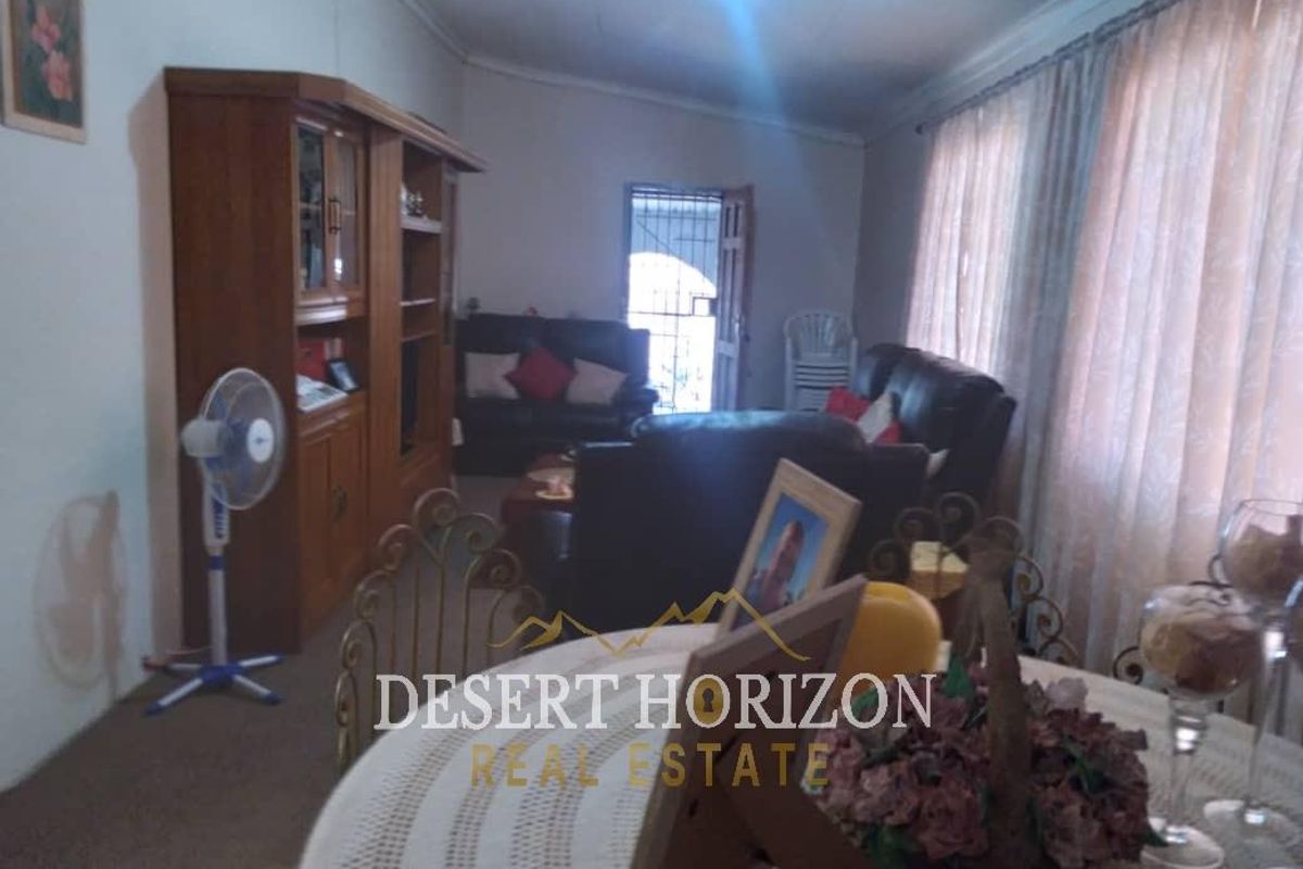 A living room area featuring a security gate at the entrance, with dated finishes and standard residential layout.