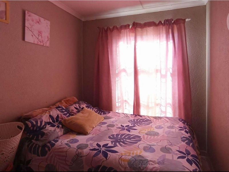 A standard bedroom featuring a window with a curtain rod, providing natural light and a functional space for rest.
