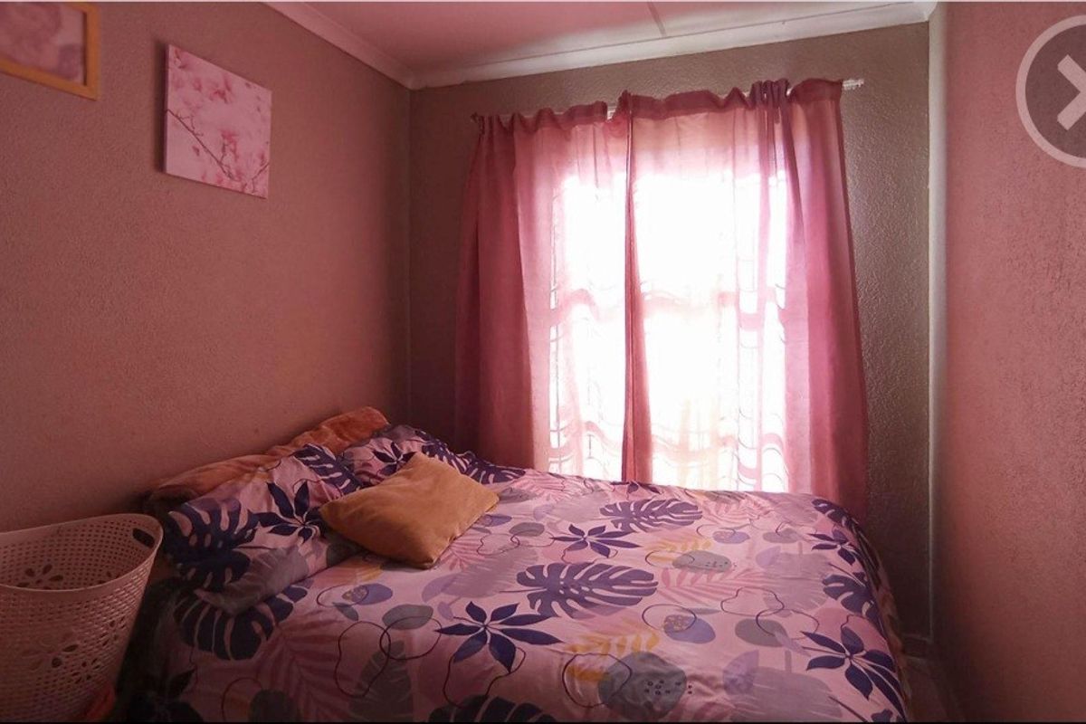 A standard bedroom featuring a window with a curtain rod, providing natural light and a functional space for rest.