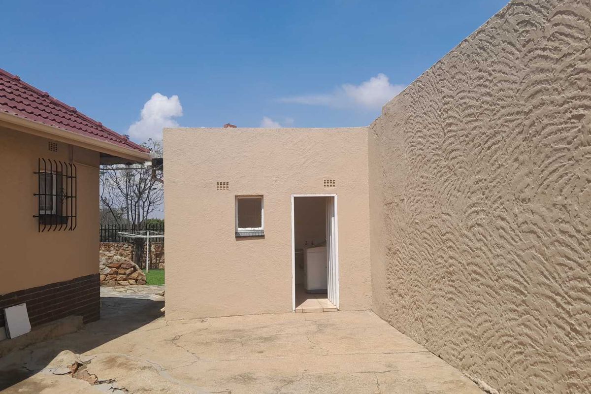 Exterior view of a utility outbuilding featuring a textured wall finish, concrete paving, and a small window, situated in a rear yard area.