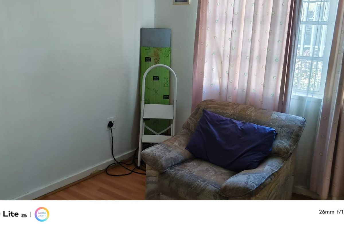 A bedroom featuring laminate flooring, a window with curtains, and a power outlet.