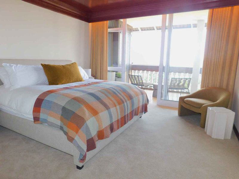 Spacious bedroom featuring neutral carpeting, a decorative recessed ceiling, and large sliding glass doors providing access to an outdoor balcony area.