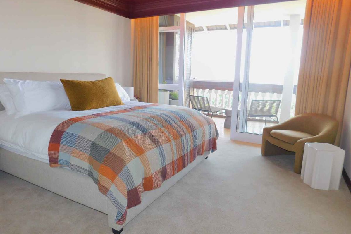 Spacious bedroom featuring neutral carpeting, a decorative recessed ceiling, and large sliding glass doors providing access to an outdoor balcony area.