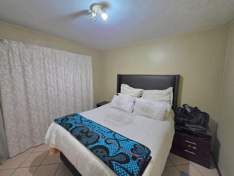 A functional bedroom featuring tiled flooring and a central ceiling light fixture, providing a neutral space ready for personalization.