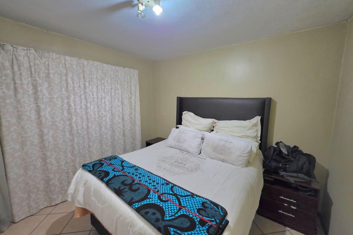 A functional bedroom featuring tiled flooring and a central ceiling light fixture, providing a neutral space ready for personalization.