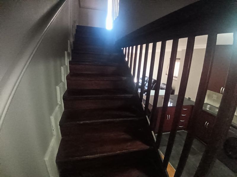 A view of a wooden staircase with a balustrade, leading to an upper level in an apartment setting.