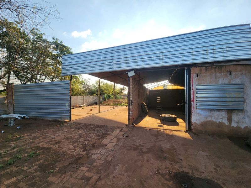An open-plan utility or workshop space featuring corrugated metal roofing and brick masonry walls, suitable for storage or industrial use.