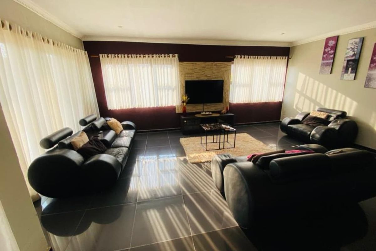 Spacious living room featuring large format floor tiles, a feature wall with stone cladding, and ample natural light through multiple windows.