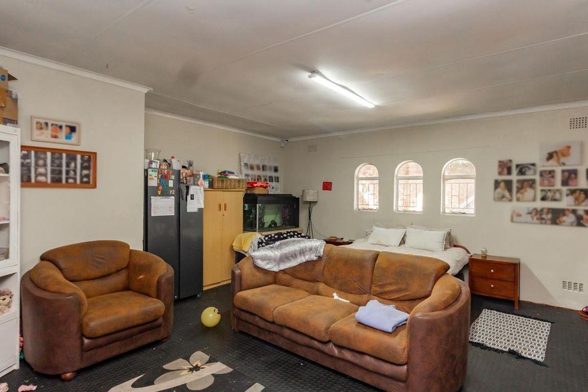 A spacious living area featuring arched windows, a ceiling-mounted light fixture, and an integrated air conditioning unit, offering potential for modernization.