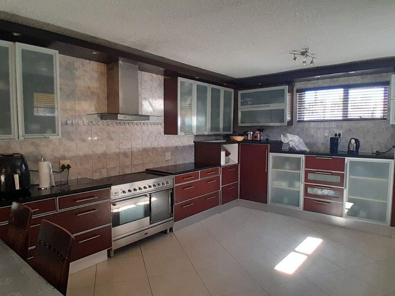 Spacious kitchen featuring dark cabinetry, granite countertops, stainless steel oven with extractor fan, and tiled flooring throughout.