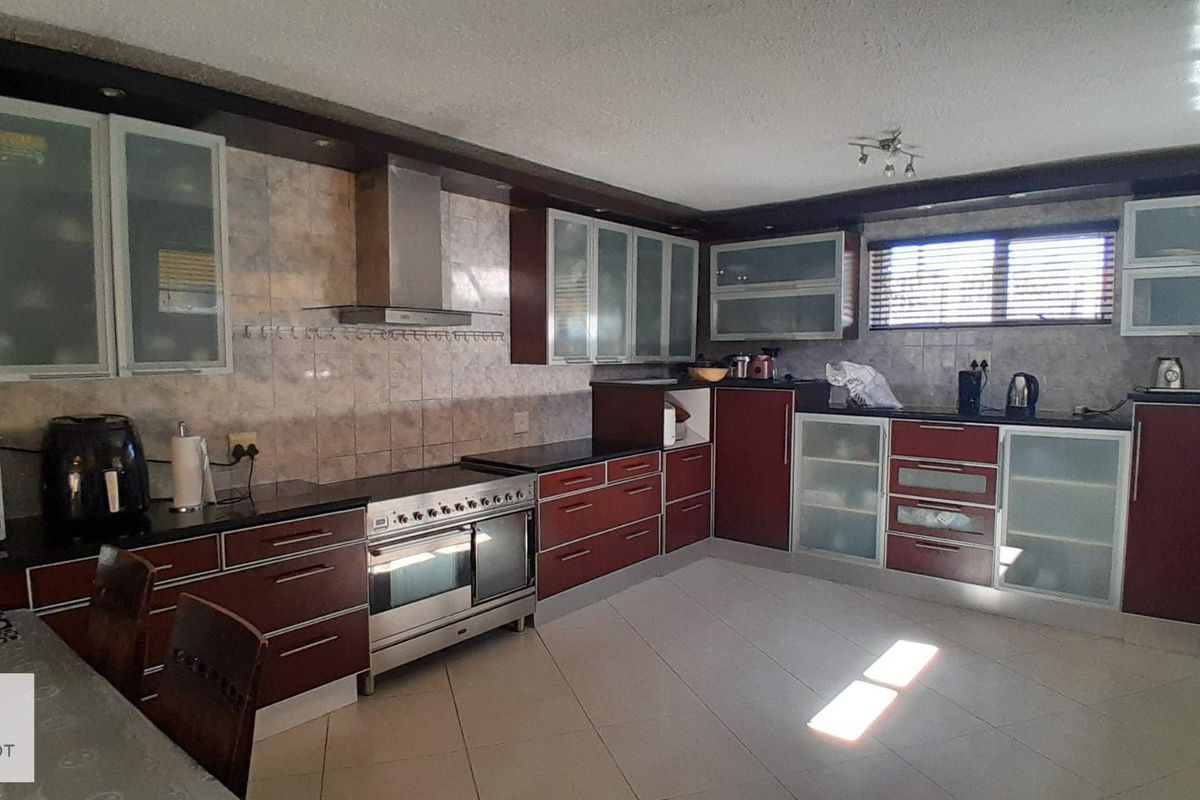 Spacious kitchen featuring dark cabinetry, granite countertops, stainless steel oven with extractor fan, and tiled flooring throughout.