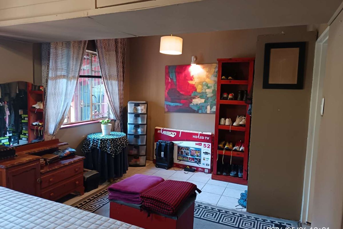 A bedroom featuring tiled flooring, a window with security bars, and built-in storage space.