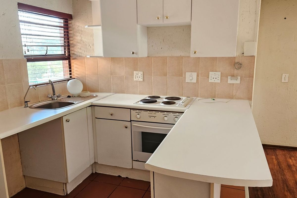 A compact, functional kitchen featuring white built-in cabinetry, laminate countertops, an electric oven and hob, and tiled backsplash, ready for a modern update.