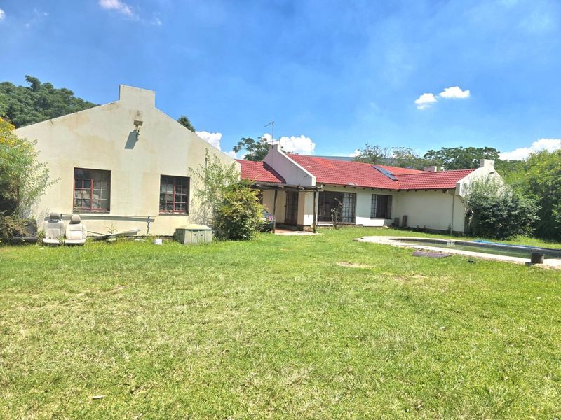 Rear view of the property featuring a swimming pool, covered patio area, and traditional gabled roof architecture set within a large garden.