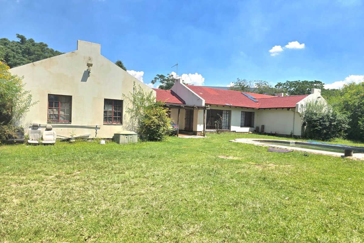 Rear view of the property featuring a swimming pool, covered patio area, and traditional gabled roof architecture set within a large garden.