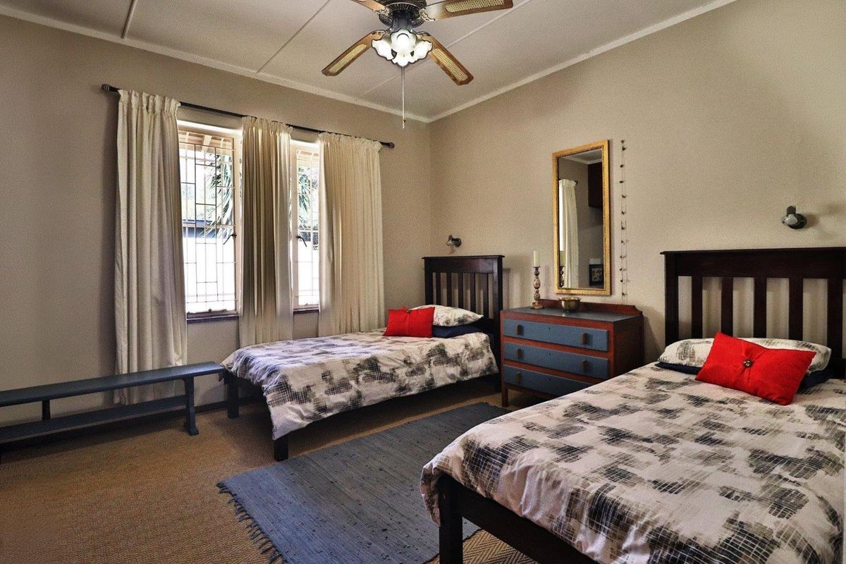 A spacious bedroom featuring a ceiling fan, wall-mounted reading lights, and security bars on the windows.