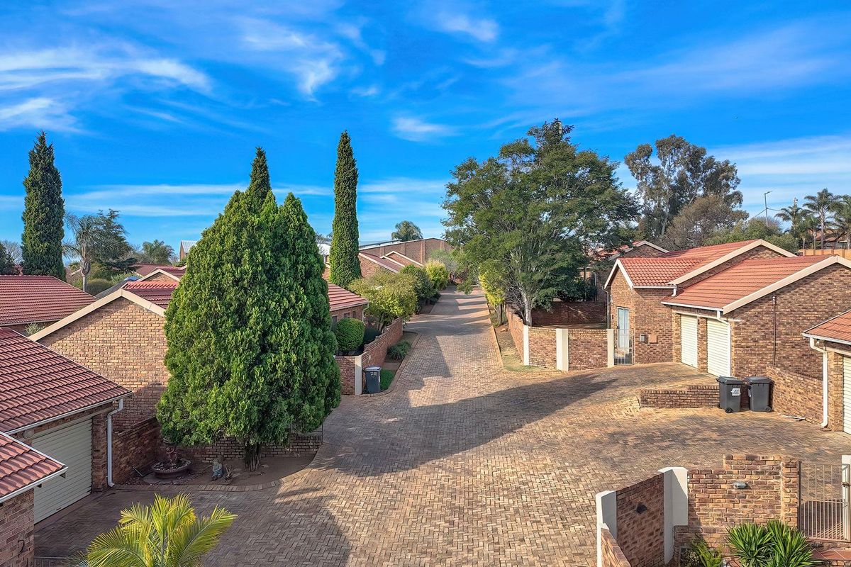 Aerial view of a residential cluster complex featuring brick-faced homes with tiled roofs and a central paved driveway.