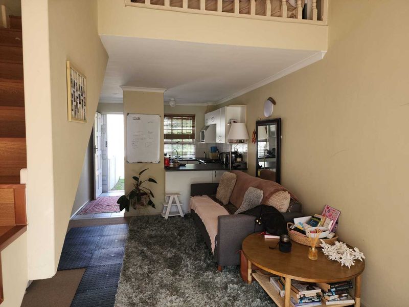 Open plan living area featuring a kitchen, staircase leading to a mezzanine level, and direct access to the exterior entrance.