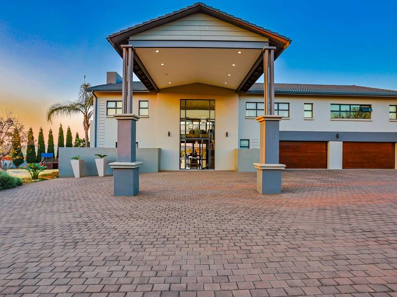Impressive front facade featuring a grand covered entrance portico, paved driveway, and double garage with modern architectural design.