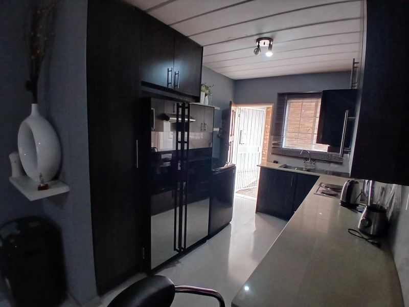 A functional kitchen featuring dark built-in cabinetry, light countertops, and a direct access door leading to an exterior area.