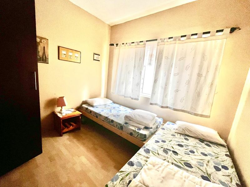 A functional bedroom featuring a built-in wardrobe and natural light through a window with installed curtain rods.