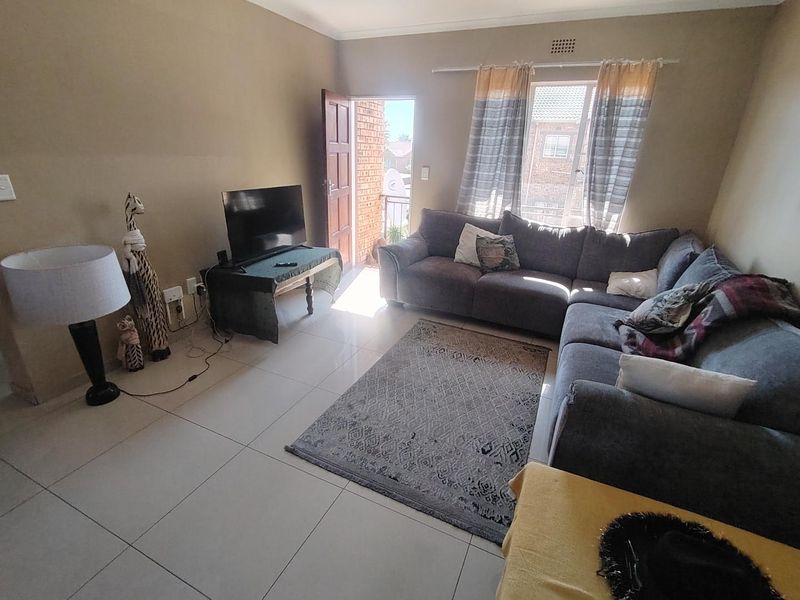 A living room featuring tiled flooring and direct access to an outdoor balcony area through a door.