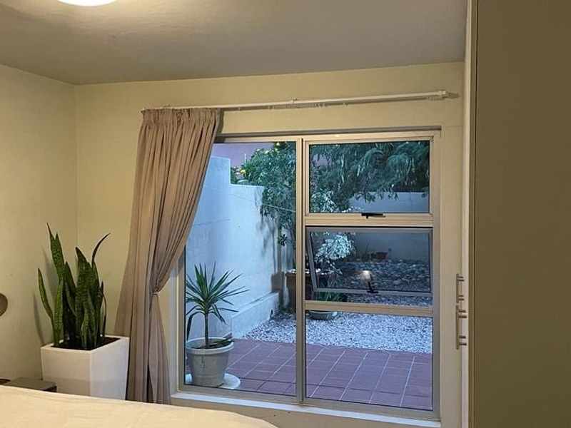 A bedroom featuring a built-in wardrobe and a window overlooking a private outdoor patio area.