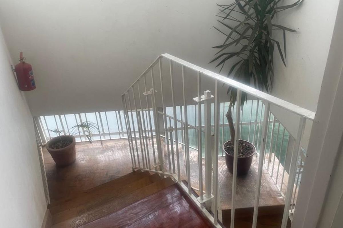 A functional interior staircase featuring parquet flooring and a white metal balustrade, providing access between levels in the apartment building.