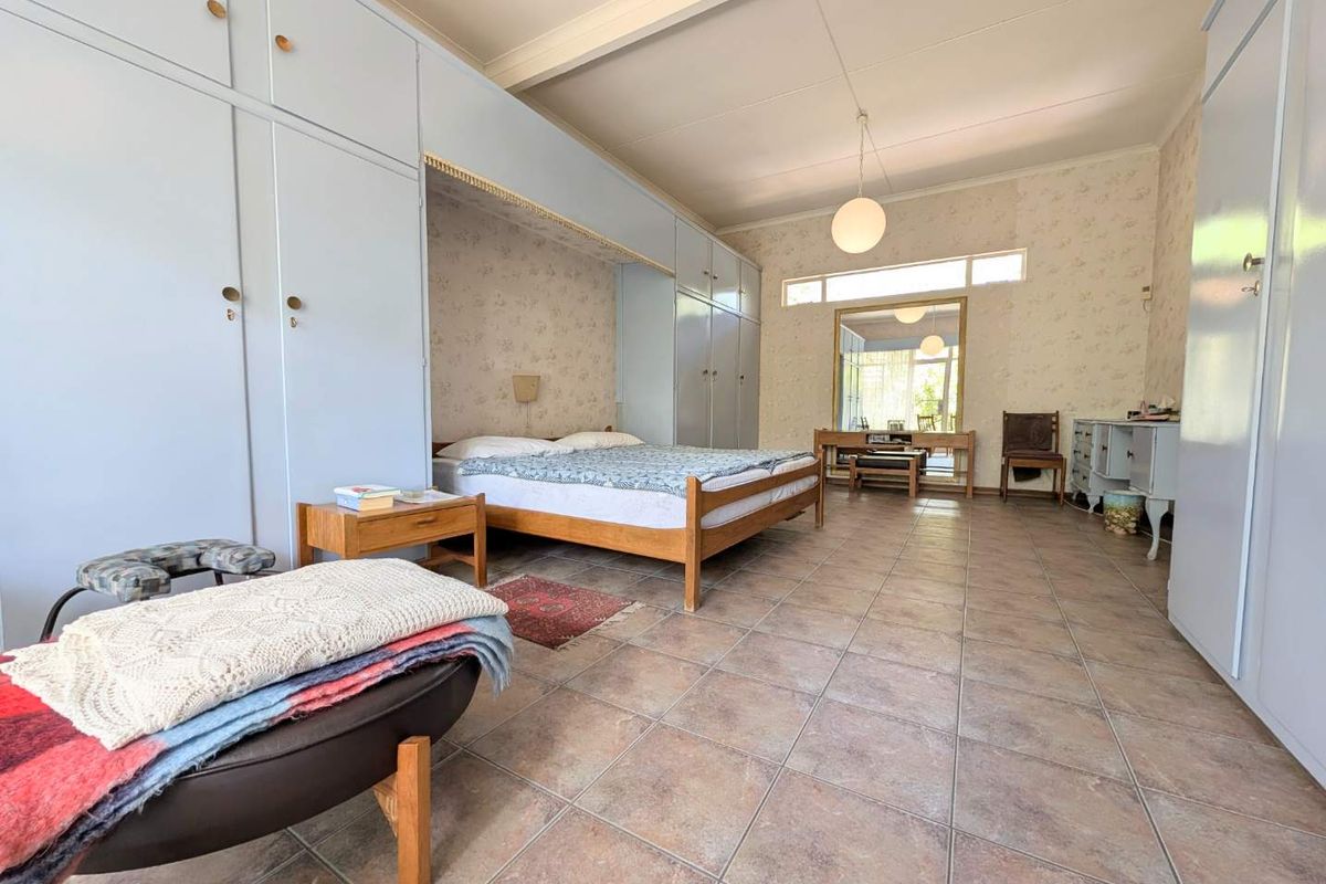 Spacious bedroom featuring extensive built-in cabinetry, tiled flooring, and large windows allowing for natural light.