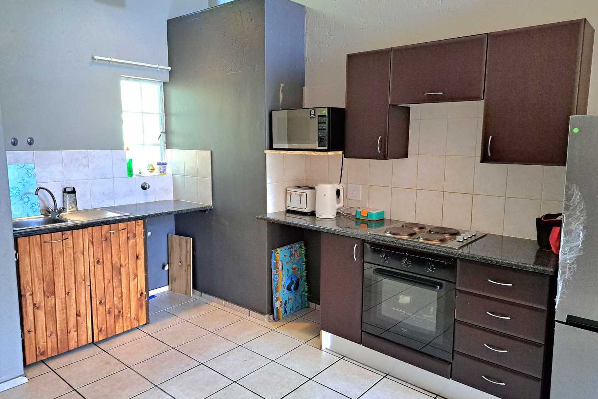 Kitchen featuring dark cabinetry, granite countertops, built-in oven, electric hob, and tiled flooring with a functional layout.