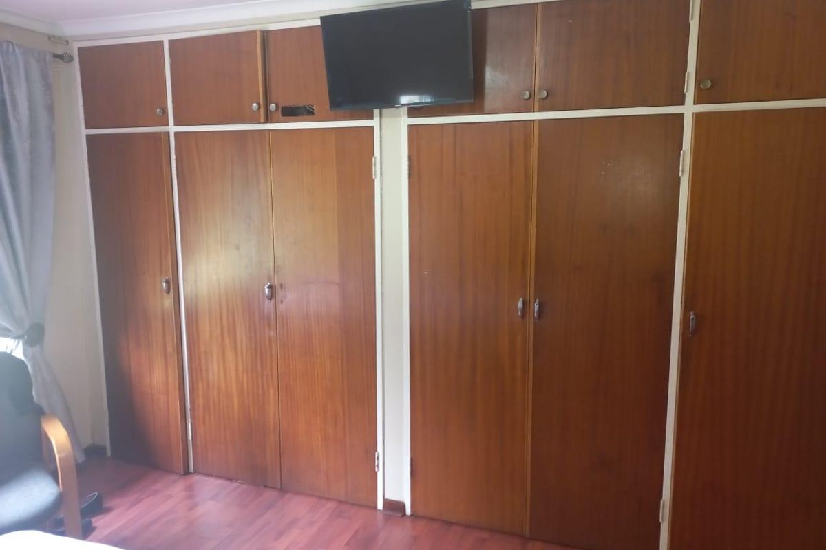 A bedroom featuring extensive floor-to-ceiling built-in wooden cabinetry providing ample storage space.