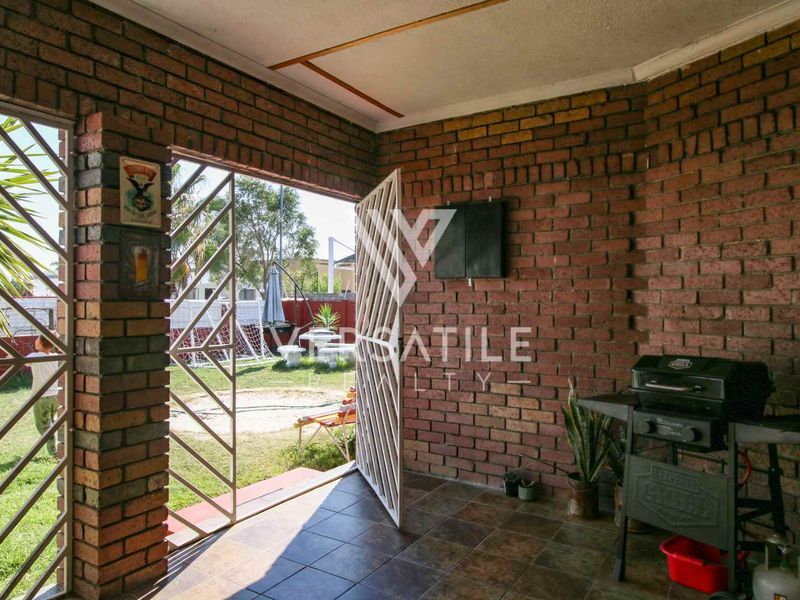 Covered outdoor patio area featuring exposed brick walls and tiled flooring, providing direct access to the rear garden.