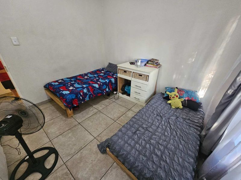 A functional bedroom featuring tiled flooring and neutral wall finishes, providing a simple and practical living space.