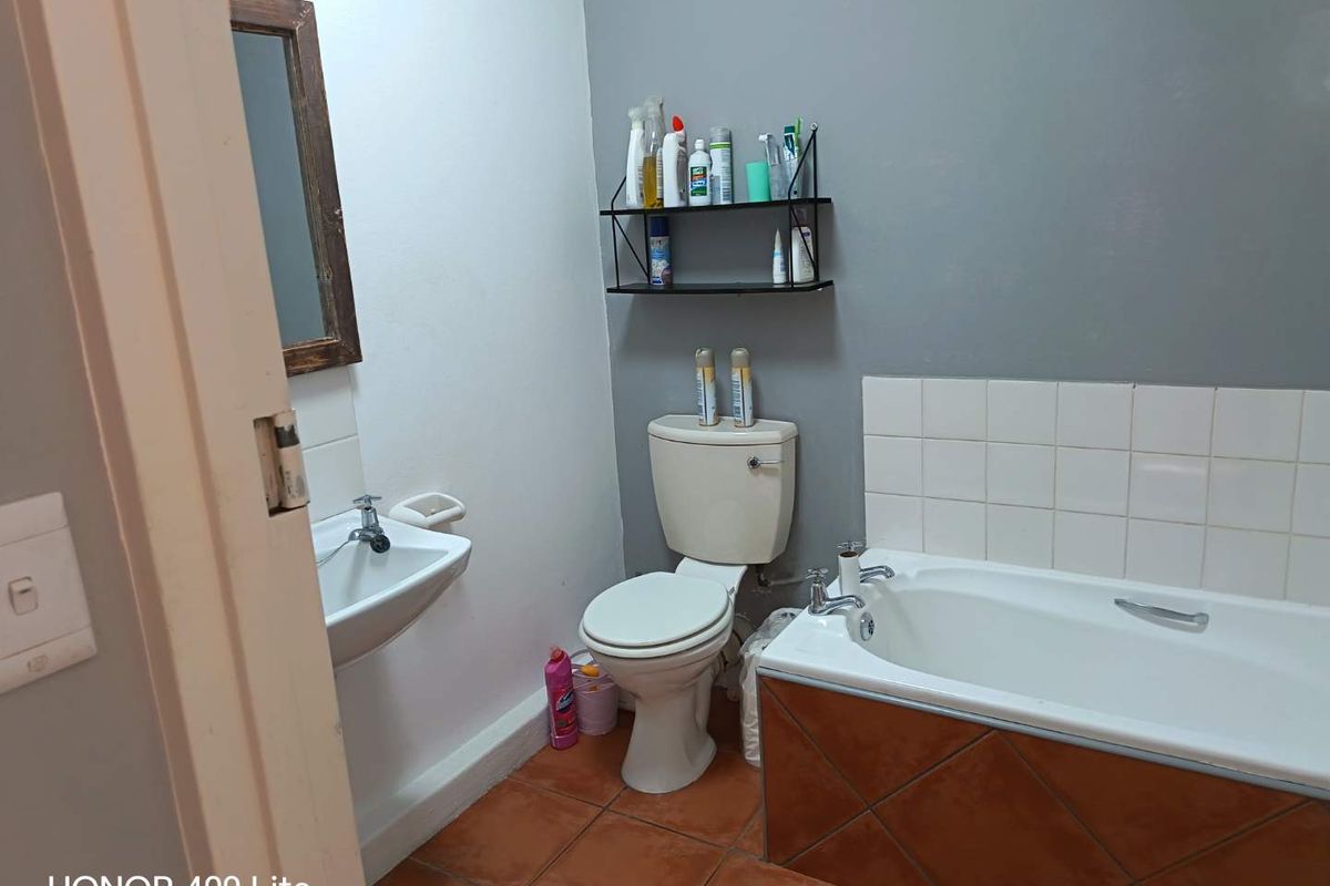 A functional bathroom featuring a standard bathtub with tiled surround, a wall-mounted basin, and a toilet.