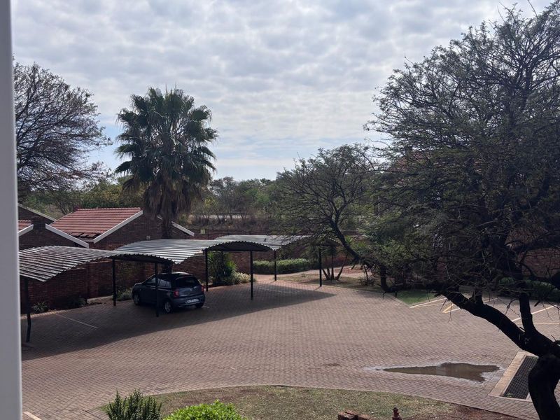 View of the complex parking area featuring paved driveway and covered carports.
