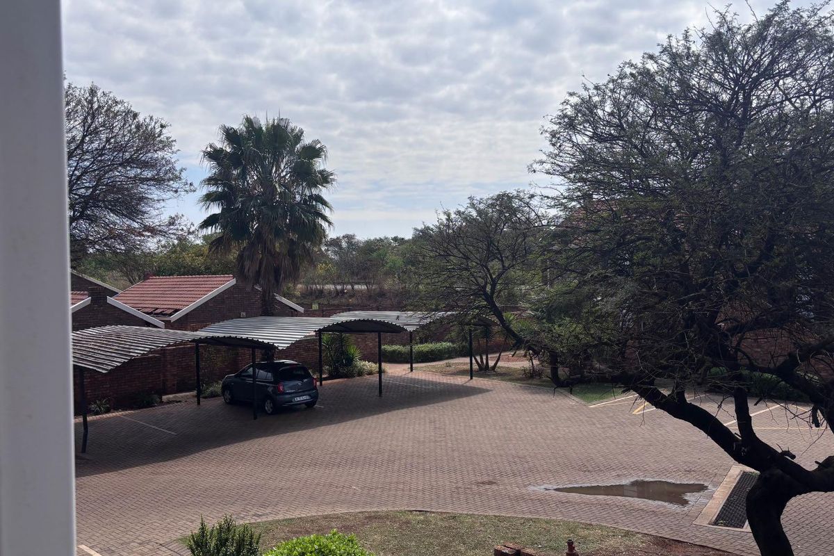 View of the complex parking area featuring paved driveway and covered carports.