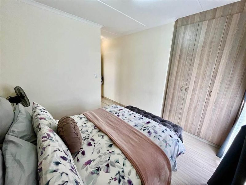 A well-maintained bedroom featuring light laminate flooring and ample built-in wooden cupboards, offering a clean and functional living space.