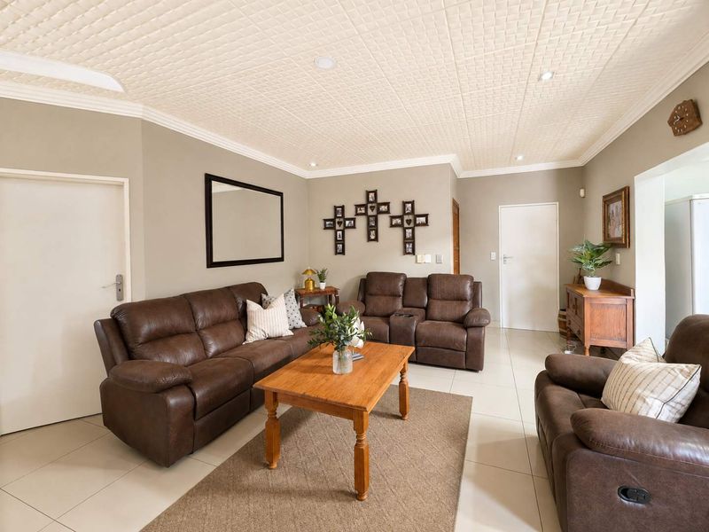 A well-maintained living room featuring neutral wall tones, tiled flooring, and a distinctive textured ceiling with recessed lighting.