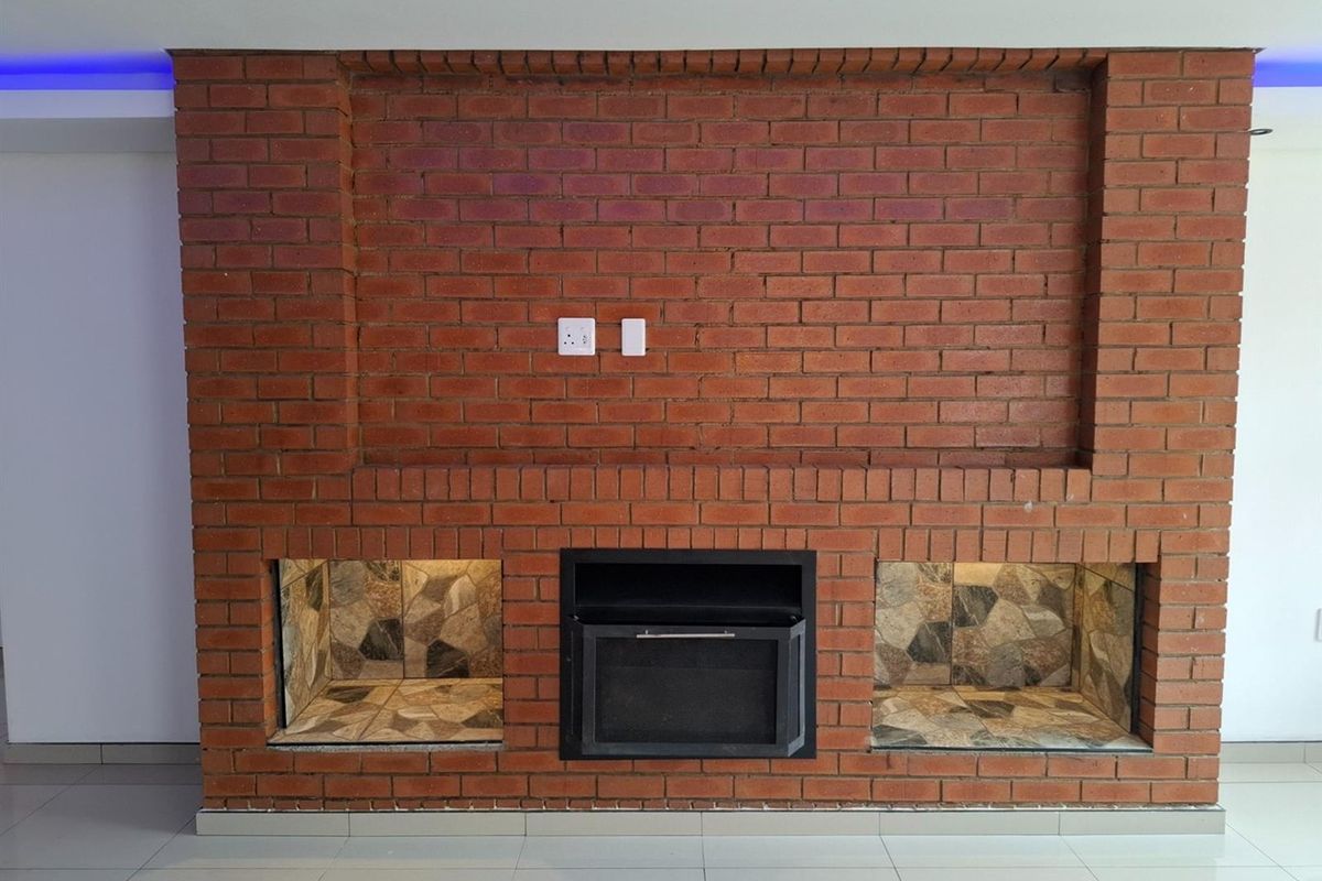 A living room featuring a prominent exposed brick wall with a built-in fireplace and integrated accent lighting.