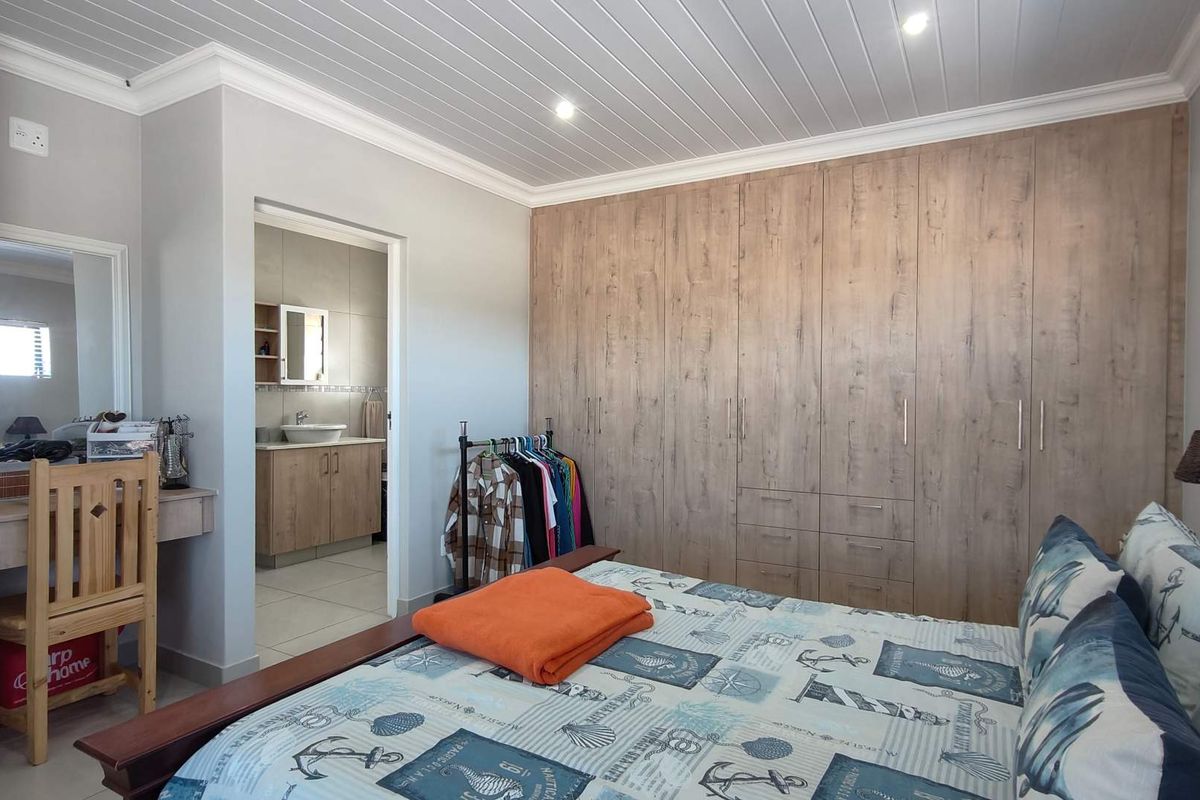 A well-maintained bedroom featuring extensive built-in wooden cabinetry, a tongue-and-groove ceiling, and an adjoining en-suite bathroom with a vanity.